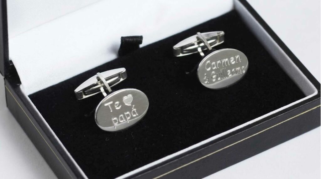 Gemelos ovalados de plata grabados con frase en estuche de regalo.