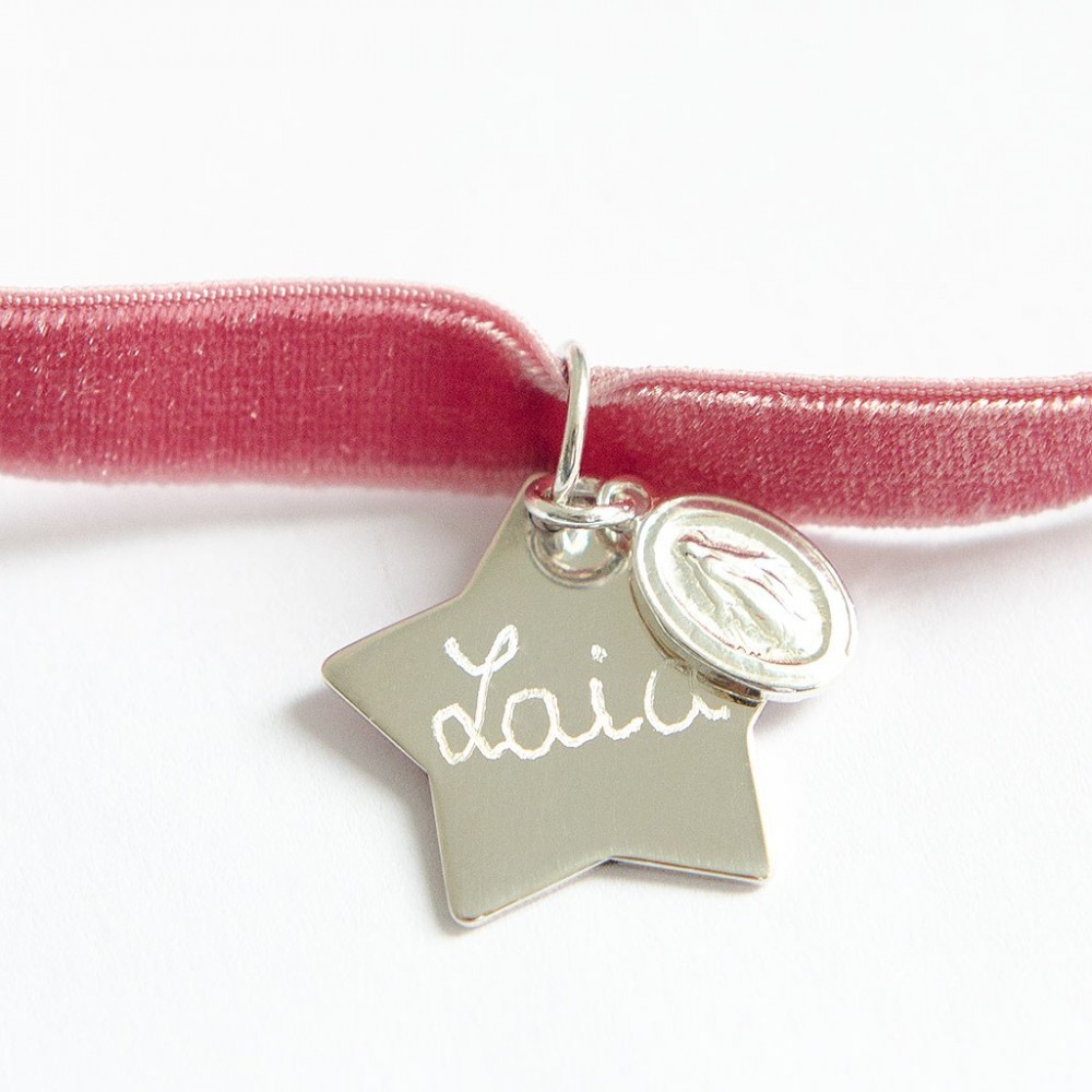 Gargantilla de terciopelo rosa con colgante de estrella de plata grabado con el nombre y una pequeña medalla de la Virgen.