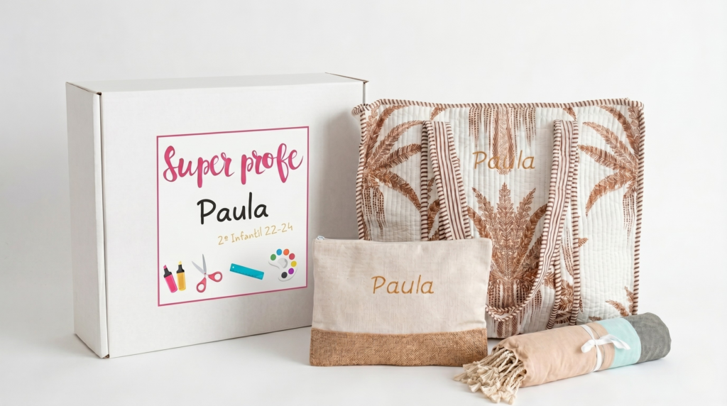 Pack de regalo para profesores que incluye una caja personalizada, un bolso de playa acolchado con estampado de palmeras marrón y el nombre bordado, un neceser a juego y una toalla pareo.