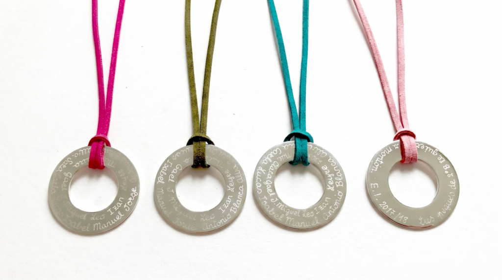 Collares de aro de plata grabados con nombres de alumnos, con cordones de colores.