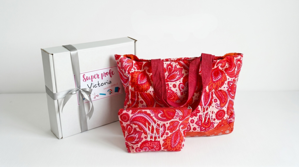 Kit de regalo personalizado para profesora con bolso de tela, neceser estampado paisley rojo y caja de regalo blanca sobre fondo limpio.