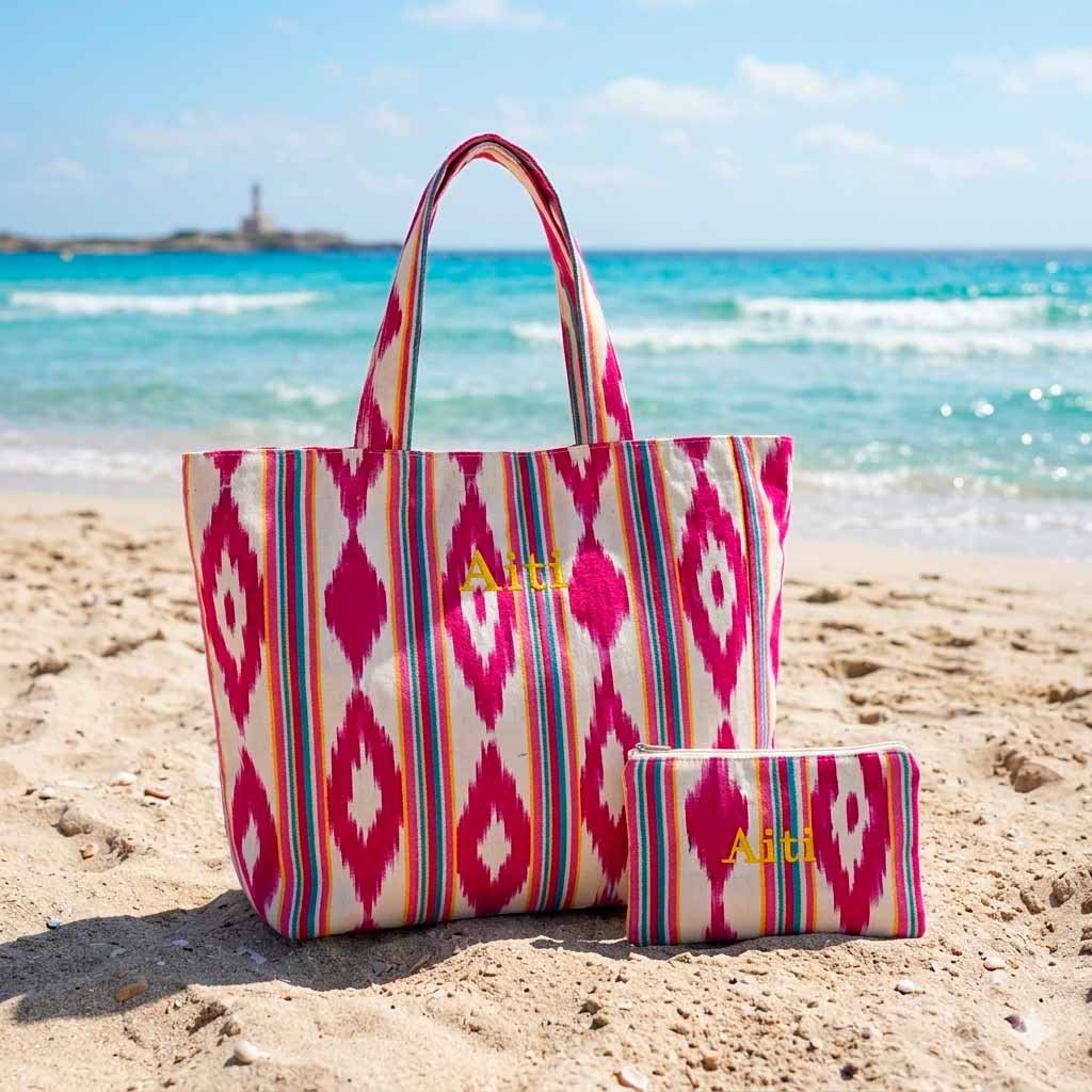 Bolsa de playa personalizada con estampado ikat y neceser a juego sobre la arena.